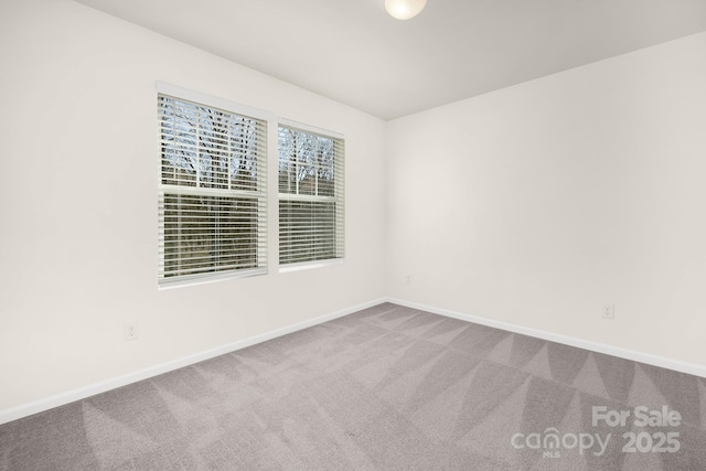 carpeted spare room featuring baseboards