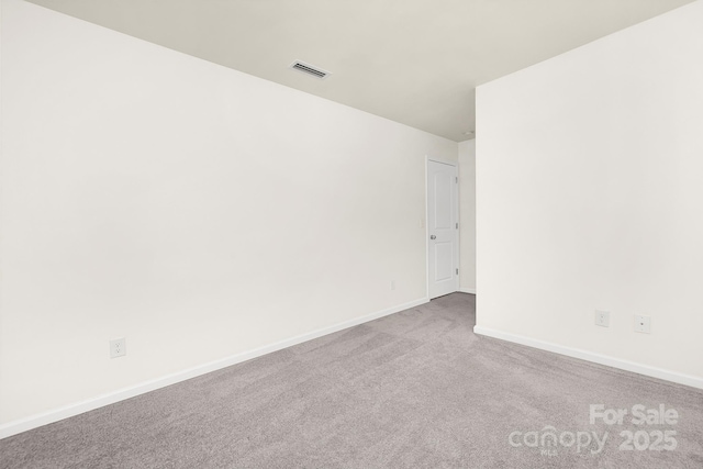 carpeted spare room with visible vents and baseboards