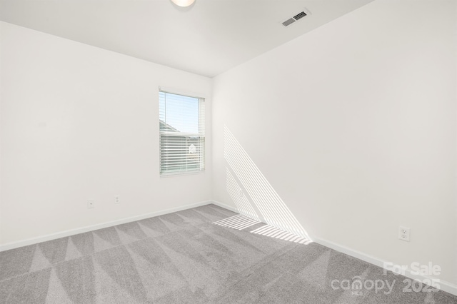 spare room with carpet floors, baseboards, and visible vents