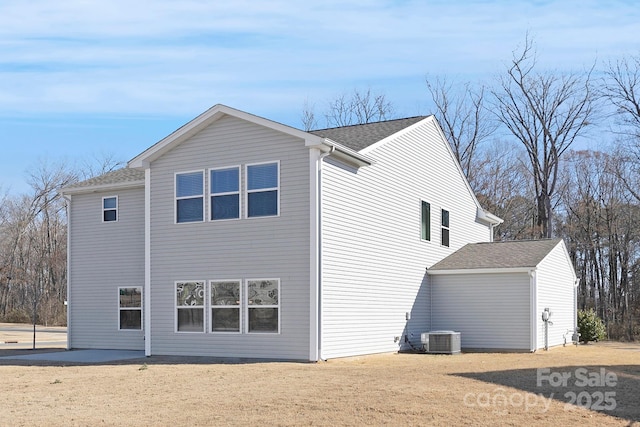 view of side of home featuring a shingled roof and central AC unit