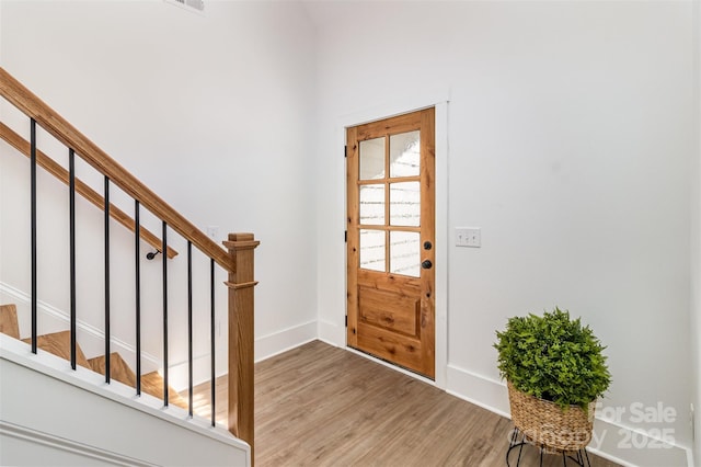 entrance foyer featuring stairs, light wood finished floors, and baseboards