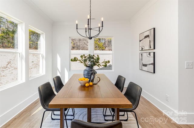 dining room with baseboards, ornamental molding, light wood-type flooring, and a notable chandelier