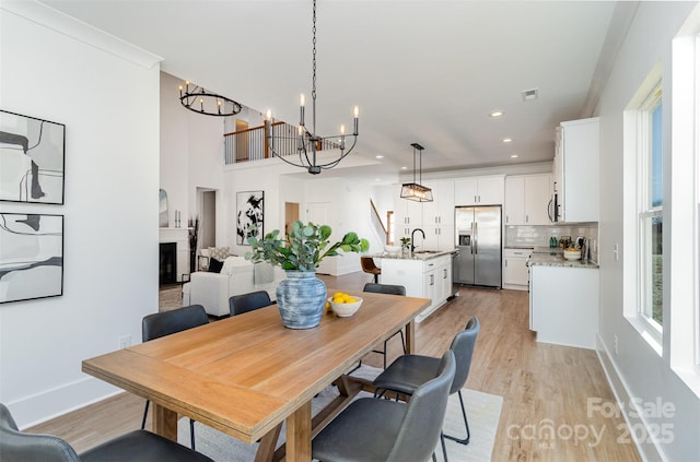 dining area featuring an inviting chandelier, light wood-style flooring, a fireplace, and visible vents