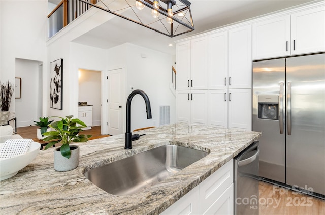 kitchen featuring appliances with stainless steel finishes, light wood-type flooring, white cabinetry, and a sink