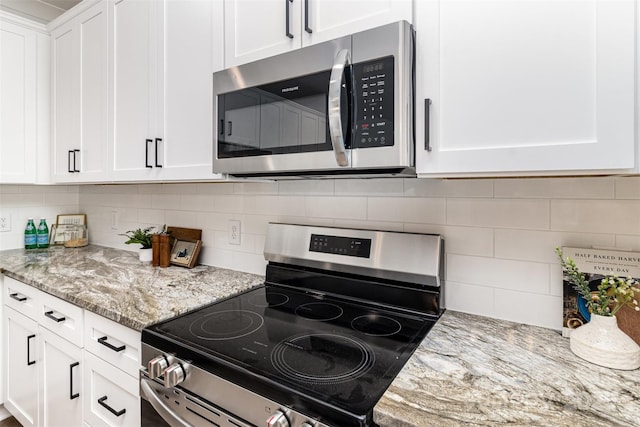 kitchen with appliances with stainless steel finishes, white cabinetry, decorative backsplash, and light stone countertops