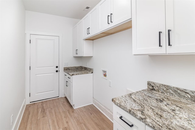 clothes washing area featuring hookup for a washing machine, visible vents, baseboards, light wood-style floors, and cabinet space