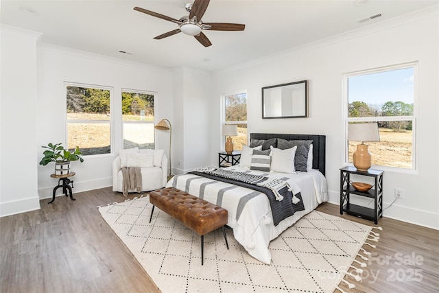 bedroom with visible vents, baseboards, a ceiling fan, wood finished floors, and crown molding