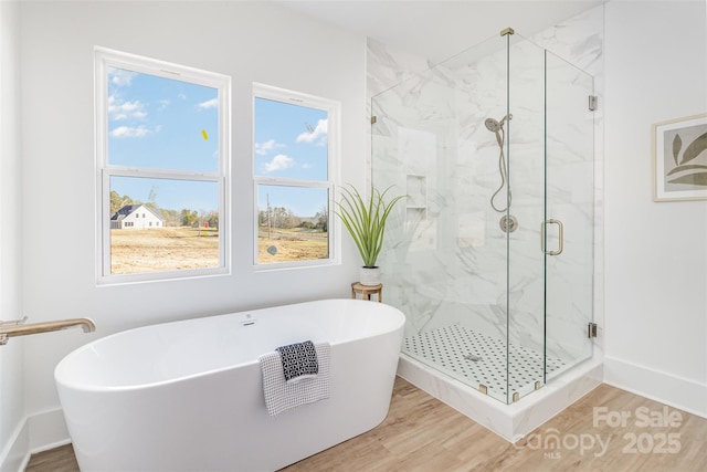 bathroom with a soaking tub, a marble finish shower, and wood finished floors