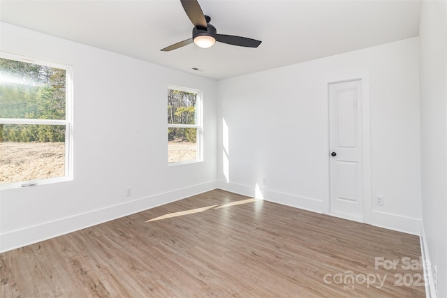 empty room with a ceiling fan, visible vents, baseboards, and wood finished floors