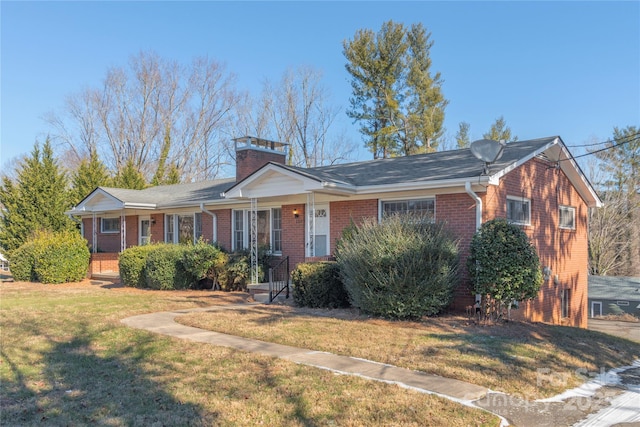 single story home featuring a chimney, a front lawn, and brick siding