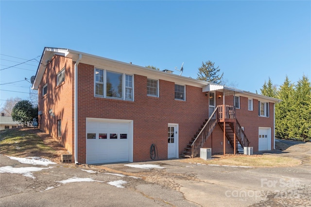 view of front of house featuring a garage, stairway, cooling unit, and brick siding