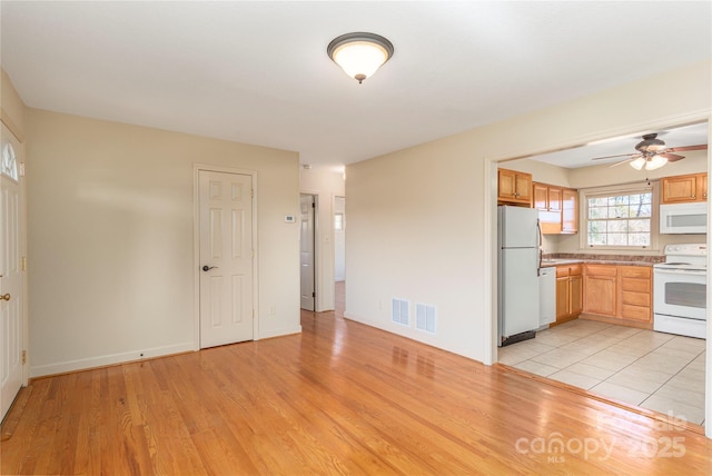 kitchen with white appliances, visible vents, light countertops, and light wood-style floors