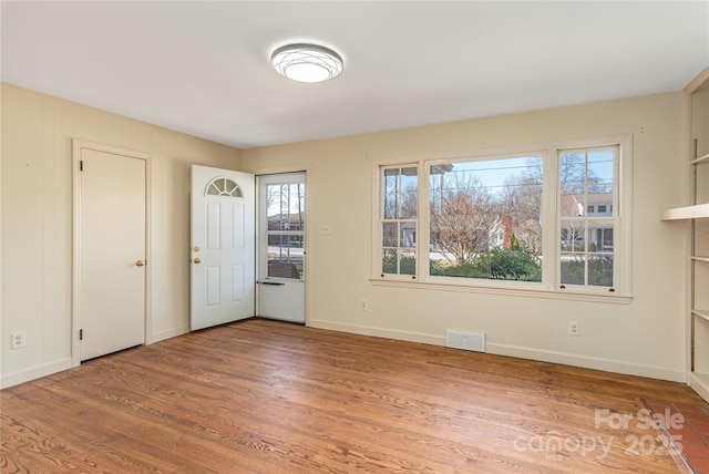 interior space with baseboards, visible vents, and wood finished floors