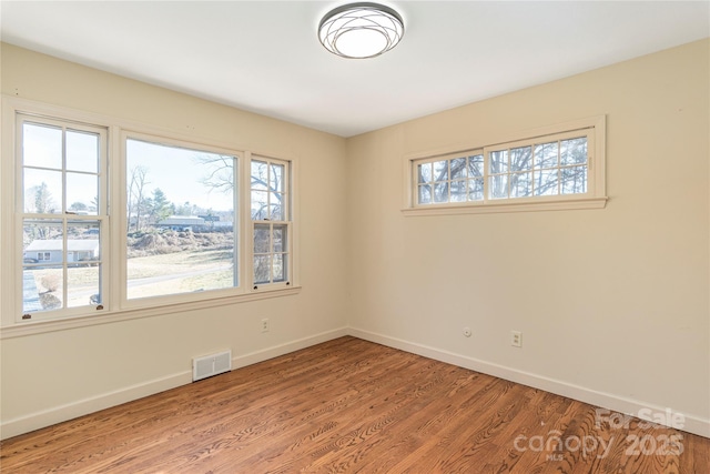 spare room with visible vents, plenty of natural light, and light wood finished floors