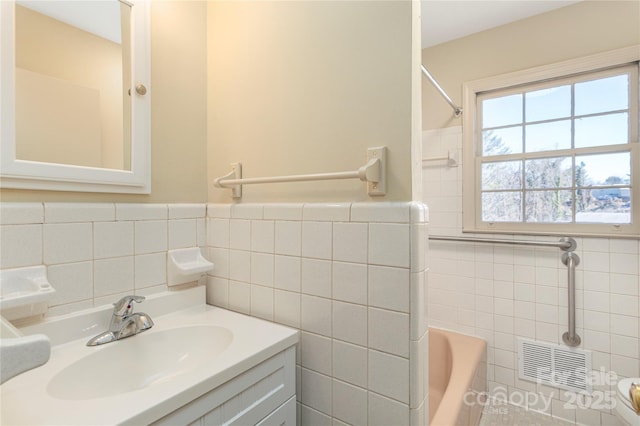 full bath featuring a bathing tub, vanity, visible vents, tile walls, and walk in shower