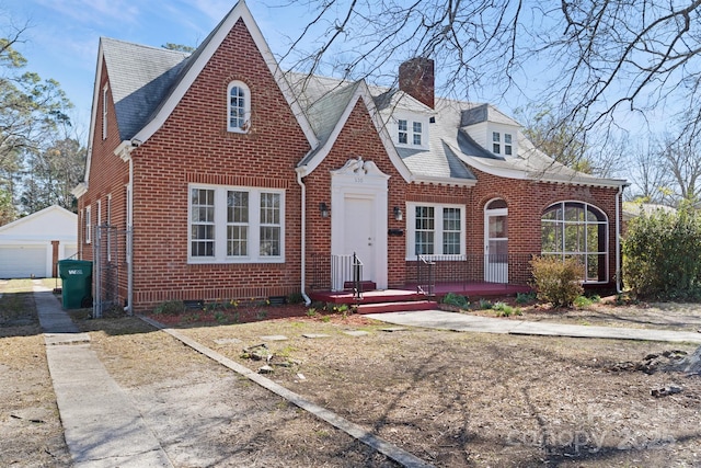 view of front of home featuring a garage, an outbuilding, brick siding, and a chimney