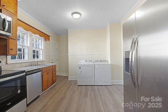 kitchen featuring stainless steel appliances, washer and clothes dryer, a sink, and brown cabinets