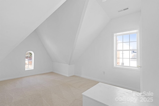 additional living space featuring light carpet, lofted ceiling, visible vents, and baseboards