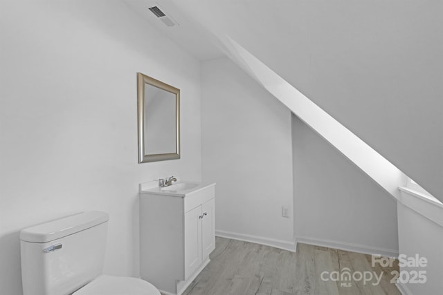 bathroom with toilet, visible vents, wood finished floors, and vanity