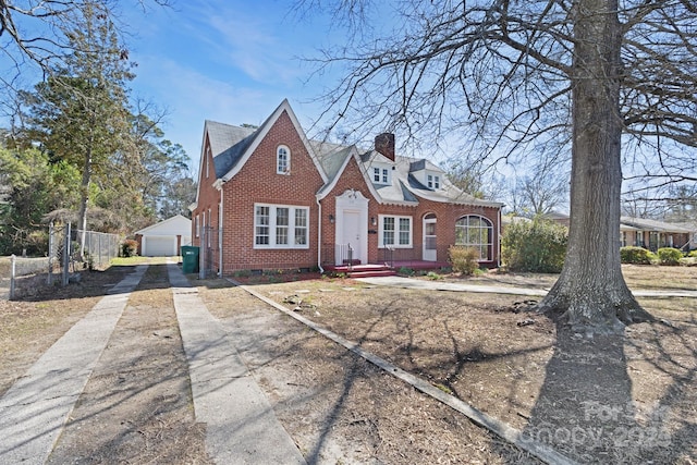 view of front of home featuring brick siding, an outdoor structure, a chimney, and fence