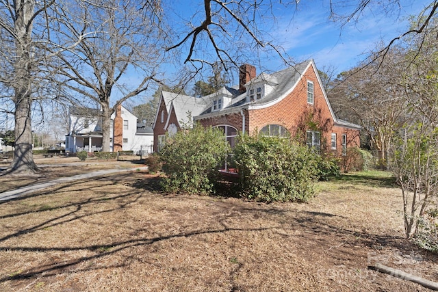 view of property exterior with a chimney and brick siding