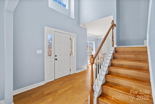 foyer with a high ceiling, stairway, wood finished floors, and baseboards