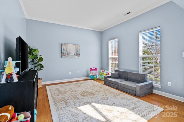 living area featuring ornamental molding, wood finished floors, visible vents, and baseboards