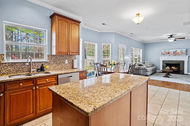 kitchen with a sink, light stone countertops, dishwasher, and a center island