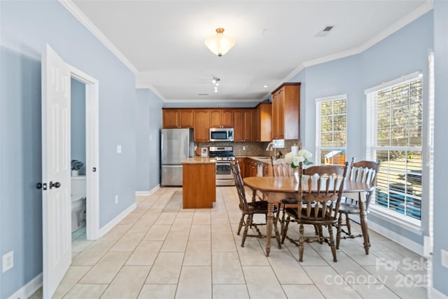 dining area with light tile patterned flooring, crown molding, visible vents, and baseboards