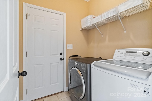 washroom with laundry area, light tile patterned flooring, and washing machine and clothes dryer