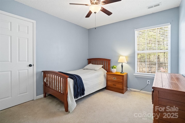 carpeted bedroom featuring baseboards, a textured ceiling, visible vents, and a ceiling fan