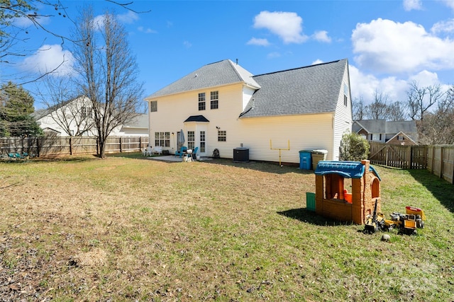 rear view of property with a patio, cooling unit, a fenced backyard, roof with shingles, and a lawn