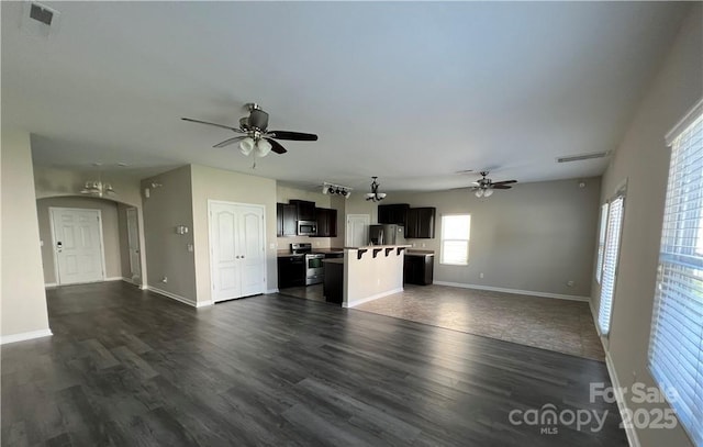 unfurnished living room with ceiling fan, dark wood-type flooring, visible vents, and baseboards