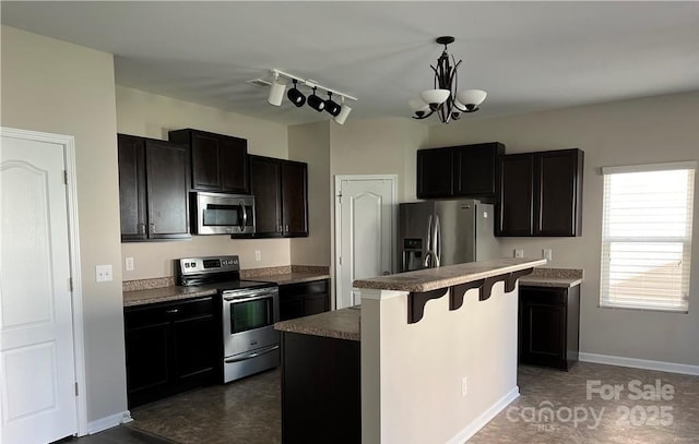 kitchen with a breakfast bar, a center island, pendant lighting, stainless steel appliances, and a chandelier