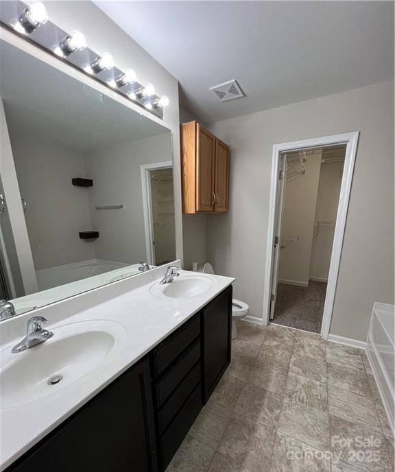 bathroom with toilet, a washtub, visible vents, and a sink