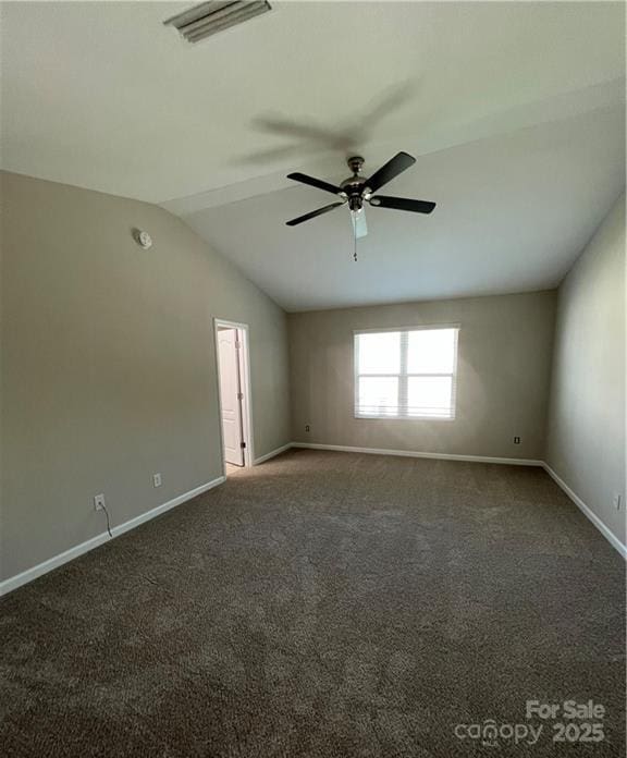 empty room with lofted ceiling, visible vents, dark carpet, a ceiling fan, and baseboards