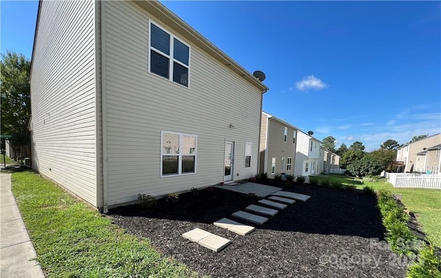 rear view of house featuring a lawn, fence, and a residential view