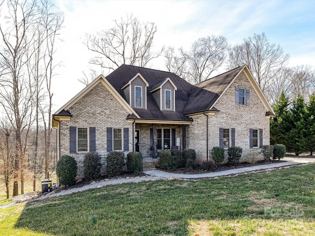 view of front facade featuring brick siding, covered porch, and a front lawn