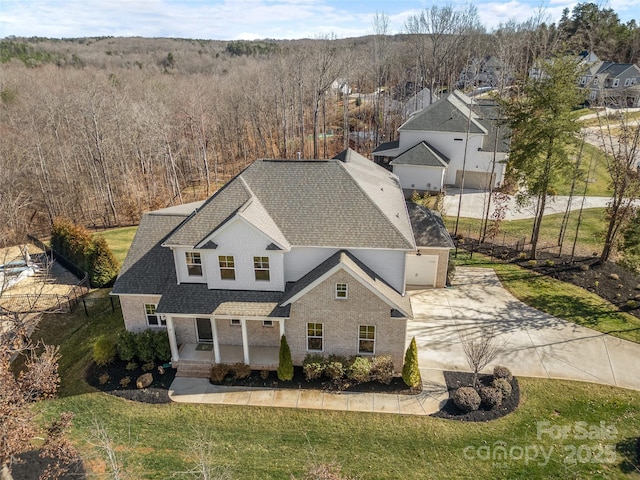 view of front of property with a shingled roof, concrete driveway, a porch, and a front lawn