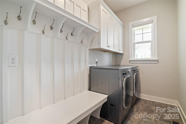 clothes washing area with cabinet space, washer and clothes dryer, and baseboards