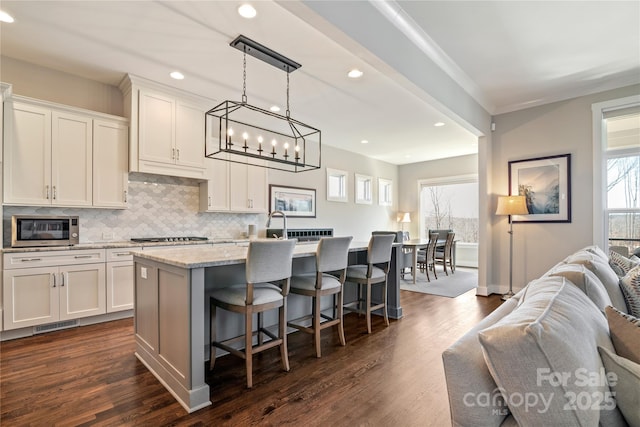 kitchen featuring open floor plan, a healthy amount of sunlight, stainless steel microwave, and decorative backsplash