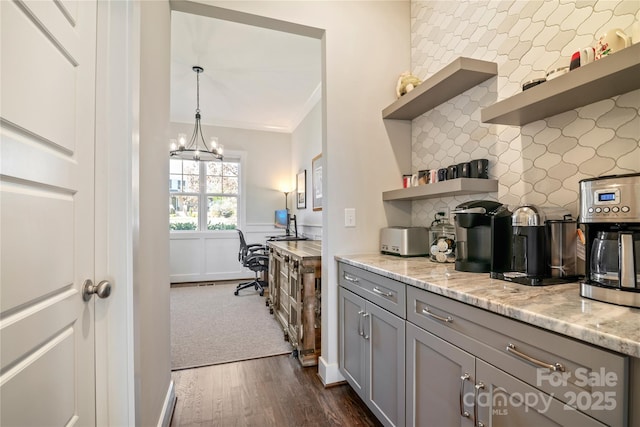 kitchen featuring dark wood-style floors, a wainscoted wall, open shelves, gray cabinets, and light stone countertops