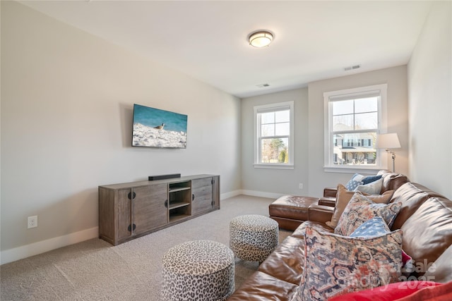 living area with baseboards, visible vents, and light colored carpet