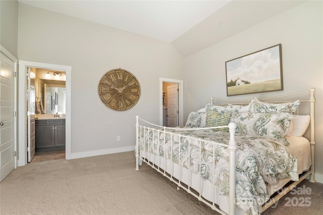 bedroom with ensuite bathroom, light carpet, vaulted ceiling, a sink, and baseboards