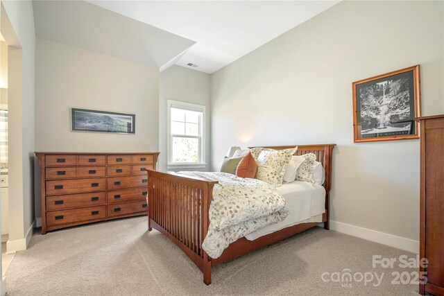 bedroom featuring lofted ceiling, visible vents, baseboards, and light colored carpet