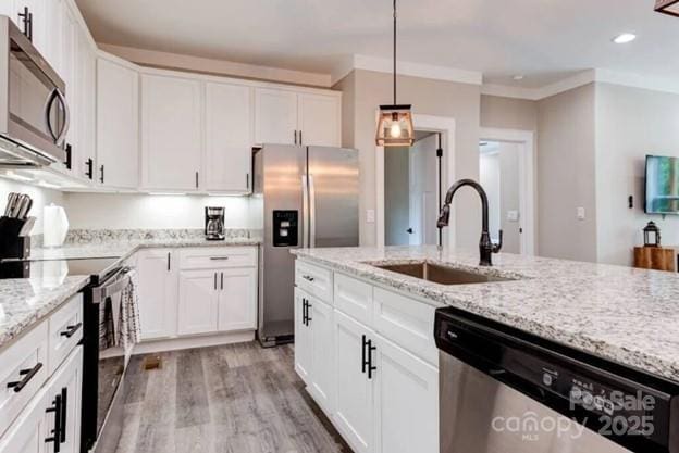 kitchen featuring appliances with stainless steel finishes, ornamental molding, white cabinetry, a sink, and light wood-type flooring