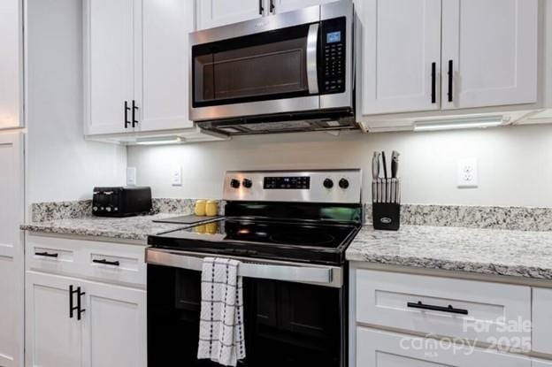 kitchen featuring light stone countertops, appliances with stainless steel finishes, and white cabinets