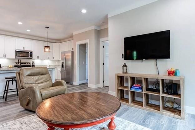 living area featuring baseboards, recessed lighting, and light wood-style floors