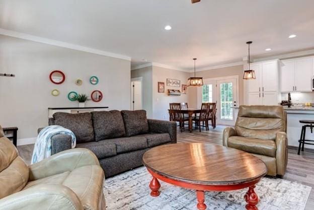 living room with ornamental molding, light wood-type flooring, and recessed lighting