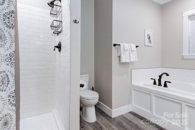 bathroom featuring toilet, wood finished floors, baseboards, a shower stall, and a bath